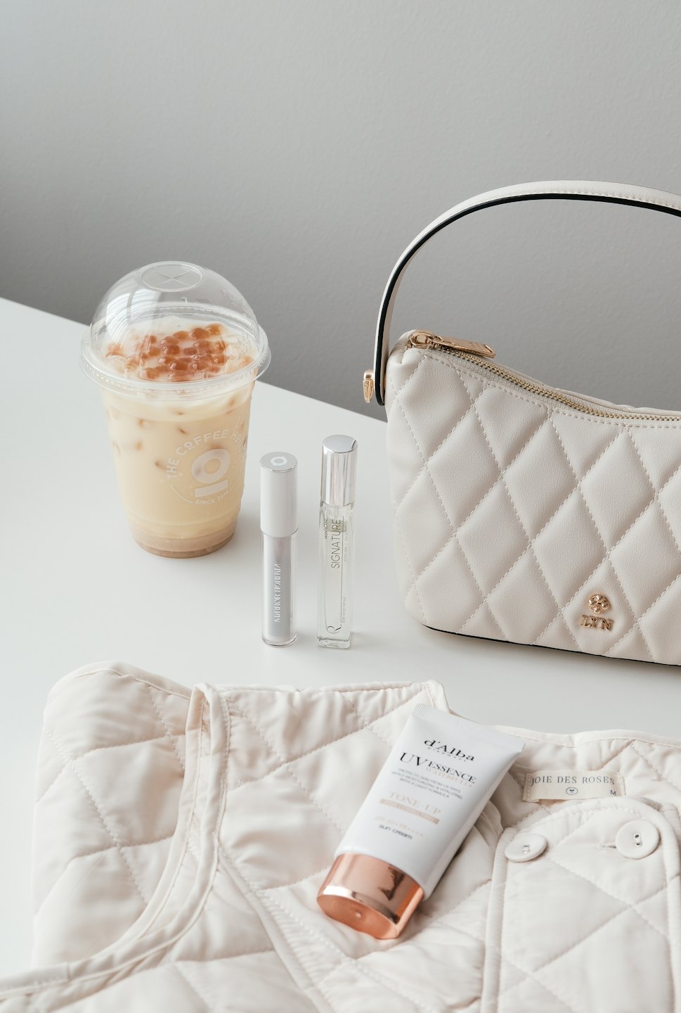 Boba tea and cream handbag with beauty products laid out.
